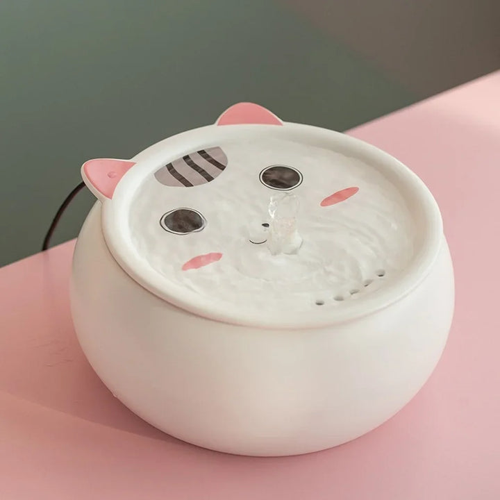 Distributeur d'eau pour animaux en céramique blanc avec oreilles de chat, design mignon et fontaine intégrée.
