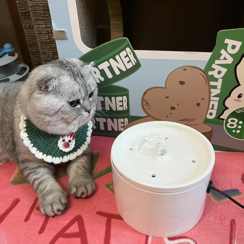 Fontaine à eau pour chat en céramique blanche, décorée d'un chat gris en col en laine verte.
