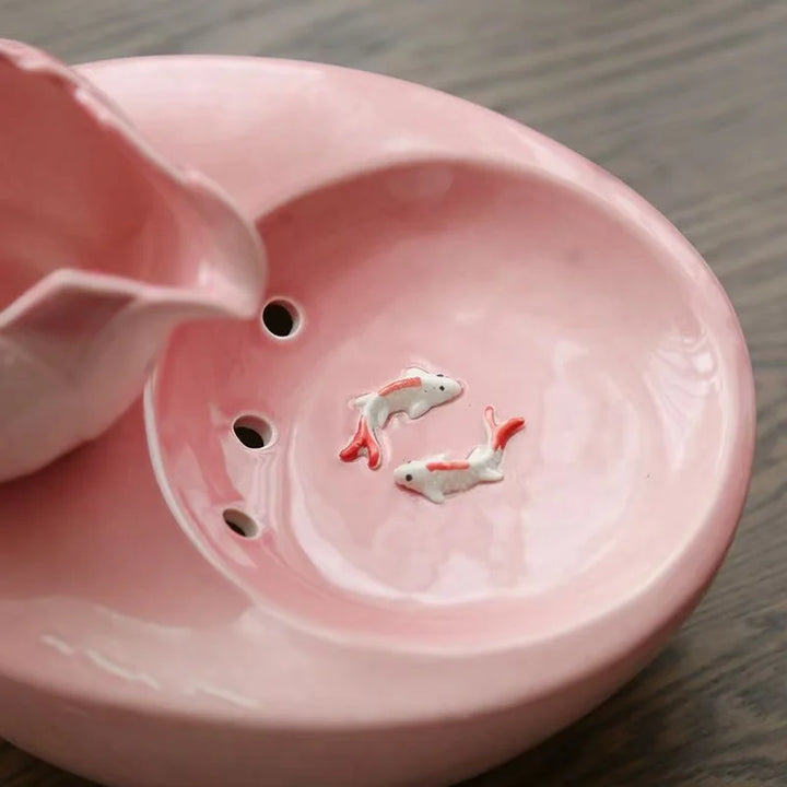 Basin en céramique rose avec poissons décoratifs et perforations, élégant et original.