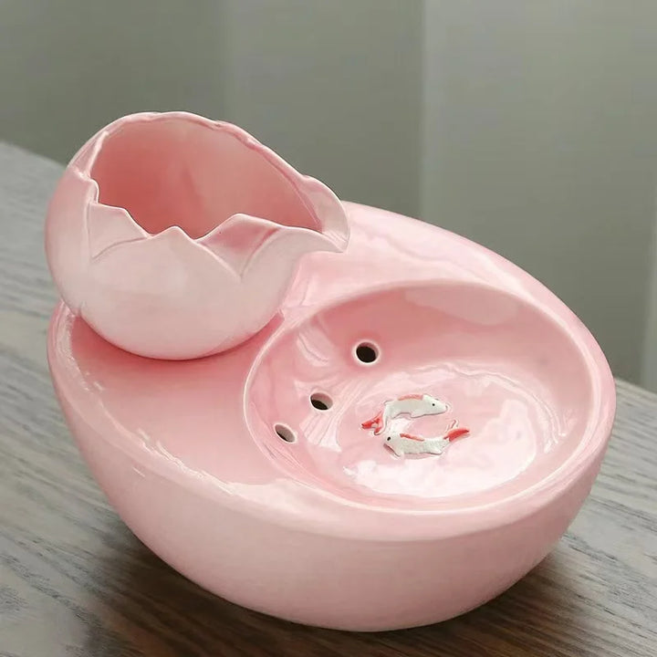 Boule en céramique rose avec poignet en forme de fleur et figurines de poissons décoratifs.